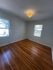 Bright room with polished hardwood floors, large windows, and a stylish ceiling light, perfect for a cozy atmosphere.