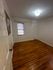 Bright room with polished hardwood floors and natural light from a large window, perfect for a cozy bedroom or home office.