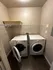 Modern laundry room with sleek appliances, featuring a stacked washer and dryer, and efficient shelving.