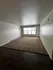 Bright and spacious living area with large window and cozy carpet, featuring mixed flooring for a stylish touch.