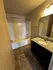 Modern bathroom with elegant granite countertop, sleek fixtures, and a spacious bathtub under warm lighting.