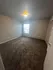 Bright and spacious bedroom featuring plush carpeting and ample natural light through a large window.