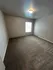 Spacious bedroom with plush carpeting, modern lighting, and a large window for natural light.