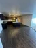 Modern kitchen with sleek dark cabinets, granite countertops, and pendant lighting on rich wooden flooring.