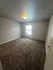 Bright and inviting bedroom with plush carpet and abundant natural light from a large window.