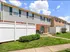 Image of townhomes showing private entrances and patios concealed by white fencing, sidewalks surrounded by professional landscaping.