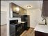 Updated kitchen showing Espresso Shaker cabinets, black appliances, and white counter with vinyl plank flooring.