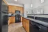 Kitchen showing black appliances, vinyl plank flooring, wood cabinets, and granite countertops.