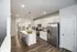 Bright modern kitchen with stainless steel appliances, large island, and elegant lighting.