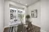 Bright dining nook with a glass table, modern chairs, and large windows overlooking townhouses.