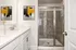 Chic bathroom with a sleek glass shower, white countertop, and contemporary artwork.