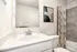 Modern bathroom featuring a sleek white vanity, abstract artwork, and stylish shower curtain.
