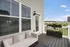 Inviting patio area with a cozy outdoor sofa, overlooking a serene suburban landscape.