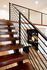 Modern wooden staircase with sleek metal railing leading to a stylish open kitchen.