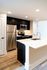 Stylish kitchen with stainless steel appliances, dark cabinetry, and chic countertops.