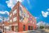 Red-brick building with a colorful mural of a trumpet player on a bright day.