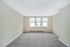 Bright, empty room with soft carpet flooring and large windows letting in natural light.