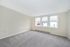 Spacious empty room with large windows and plush carpet, filled with natural light.