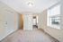 Spacious apartment entrance with plush carpeting, a cozy window nook, and a view into a modern kitchen.