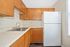 Modern kitchen with sleek wooden cabinets, stainless steel sink, and large white refrigerator.