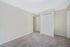 Bright and airy bedroom with soft carpet flooring and a built-in closet.