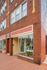 Inviting brick building with large front windows showcasing hanging plants.