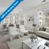 Bright and elegant living room with modern furnishings, natural light, and a dining area, offering $200 off monthly rent.