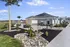 Charming outdoor area of a modern home featuring lush landscaping, a spacious patio with seating, and solar panels under a clear blue sky.