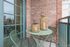 Charming balcony with brick walls, adorned with stylish wicker lanterns on a green bistro table, perfect for relaxing.