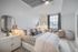 Elegant bedroom with cozy seating area, modern decor, and large window offering plenty of natural light.