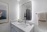 Modern bathroom featuring sleek mirror with ambient lighting, elegant white countertop, and stylish decor.