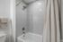 Elegant bathroom showcasing a modern tub with sleek tile walls and a plush towel, creating a serene spa-like atmosphere.