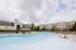 Inviting community pool at modern apartment complex with elegant architecture, surrounded by lush greenery and lounge chairs for relaxation.