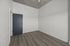 Modern apartment interior featuring sleek wooden flooring, an elegant blue door, and clean white walls with a contemporary concrete ceiling.