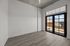 Bright and airy room with floor-to-ceiling windows and sleek wood flooring, opening to a balcony with city views.