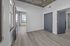 Modern apartment interior featuring light wood flooring, large windows with natural light, and sleek blue doors, offering a refreshing and spacious ambiance.