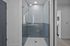 Elegant modern bathroom with sleek glass shower, stylish blue tiles, and ambient lighting.