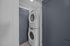 Sleek apartment laundry area featuring a stacked washer and dryer against stylish blue doors, offering modern convenience.