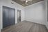 Bright modern room with sleek wood flooring, featuring a stylish ceiling fan and dark double doors leading to a private bathroom.
