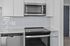 Modern kitchen featuring sleek stainless steel appliances, polished white cabinetry, and a glossy subway tile backsplash.