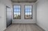 Bright modern room with large windows offering a stunning cityscape view, sleek grey door, and elegant wood flooring.