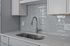 Modern kitchen design featuring a sleek grey tile backsplash, elegant stainless steel faucet, and pristine white cabinetry.