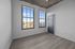 Bright and airy apartment room with large windows offering stunning views of the cityscape and elegant wood flooring.