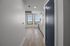Contemporary apartment hallway leading to a bright living area with large windows and modern kitchen finishes.