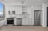 Modern kitchen with sleek stainless steel appliances, bright cabinetry, and expansive windows offering a cozy and functional space.