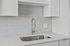 Modern kitchen with sleek marble countertop, elegant stainless steel sink, and stylish white cabinetry.