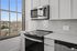 Bright, modern kitchen with sleek white cabinetry, stainless steel appliances, and an expansive window offering scenic views.