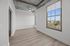 Bright, modern apartment room with large windows, stylish wooden flooring, and an industrial concrete ceiling.