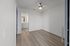 Inviting room with modern ceiling fan, sleek wood flooring, and a glimpse into a stylishly lit bathroom.
