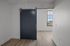 Chic apartment interior featuring a modern navy sliding barn door leading to a bright room with elegant wooden floors and a sunlit window view.